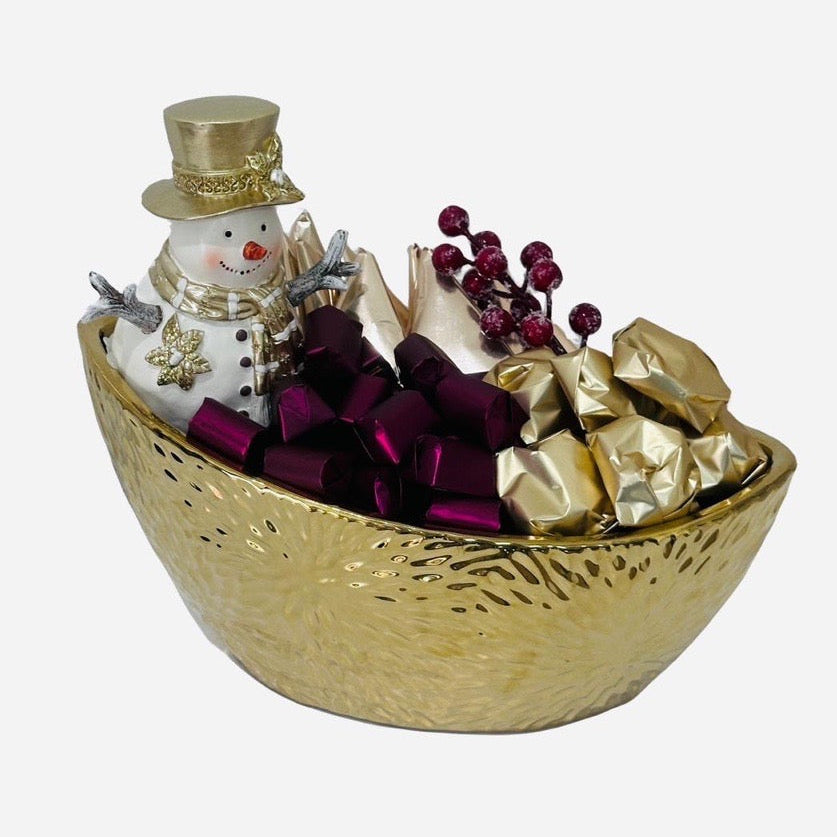 Decorative bowl with a snowman figurine, ribbons, and wrapped items on a white background