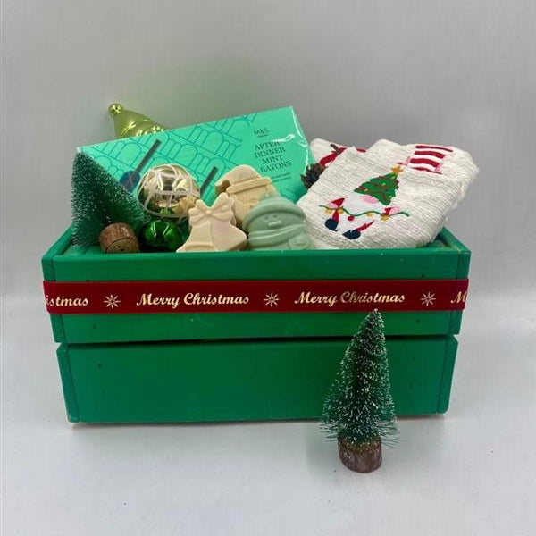 Decorative Christmas items including a green wooden box, small tree, Chocolate Batons box, Christmas towels, natural handmade soaps, and Christmas ornaments