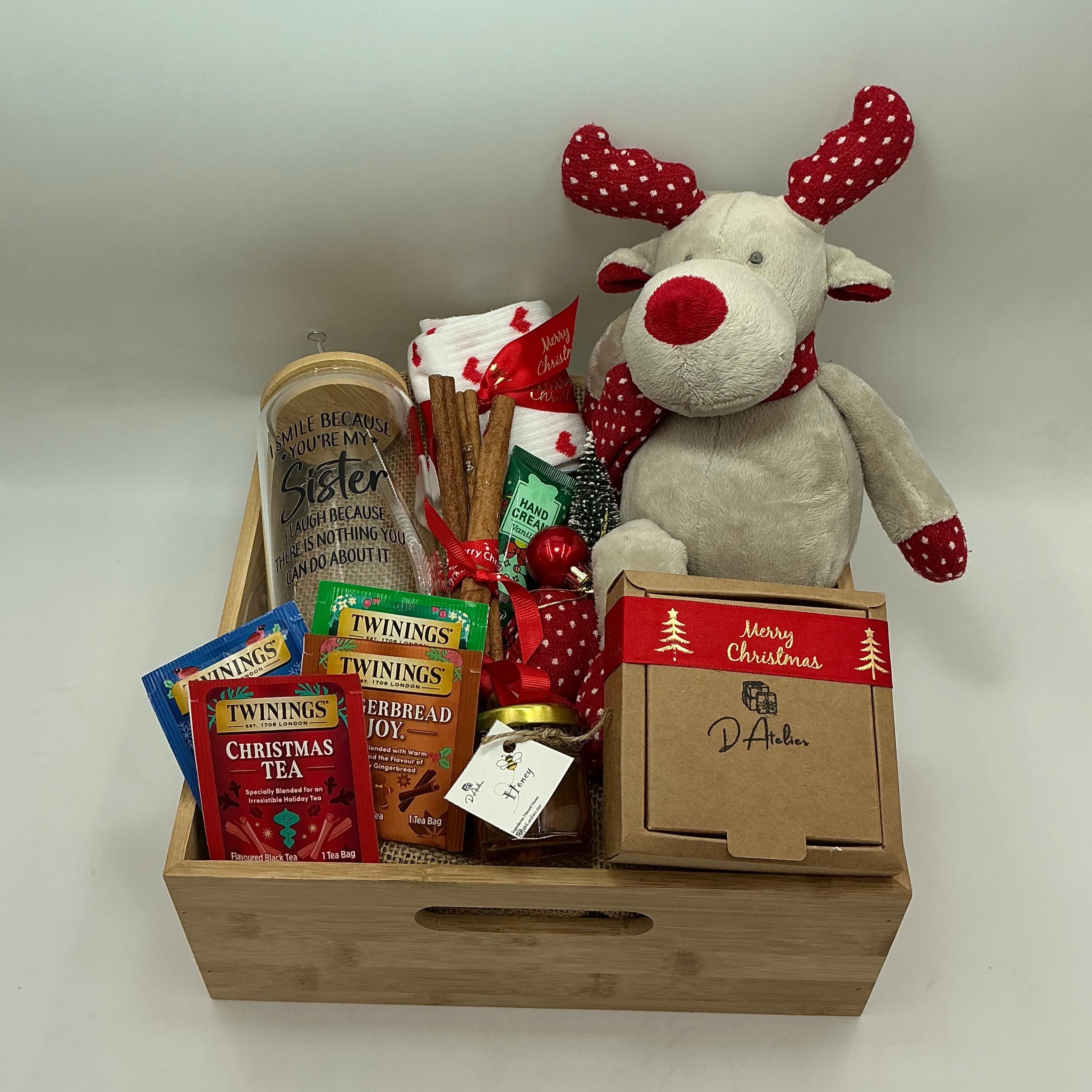 A hamper for my sister and best friend, a plus reindeer, Christmas ornaments, a glass tumbler, hand cream, cinnamon sticks, honey jar, 4 tea sachets, natural handmade soap, socks.