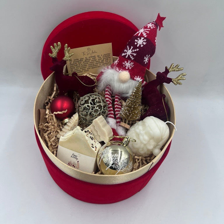 Decorative gift box with Christmas-themed items including a gnome, ornaments, and a card on a white background.