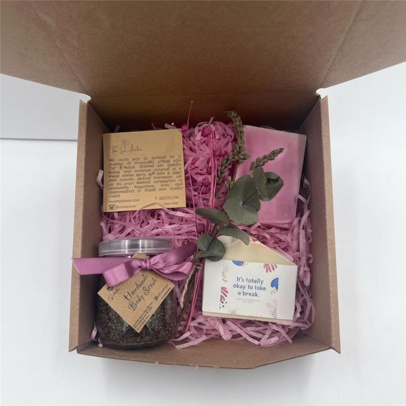 Box for women empowerment containing soaps, soap with a tag message, body scrub jar, eucalyptus and dry flowers