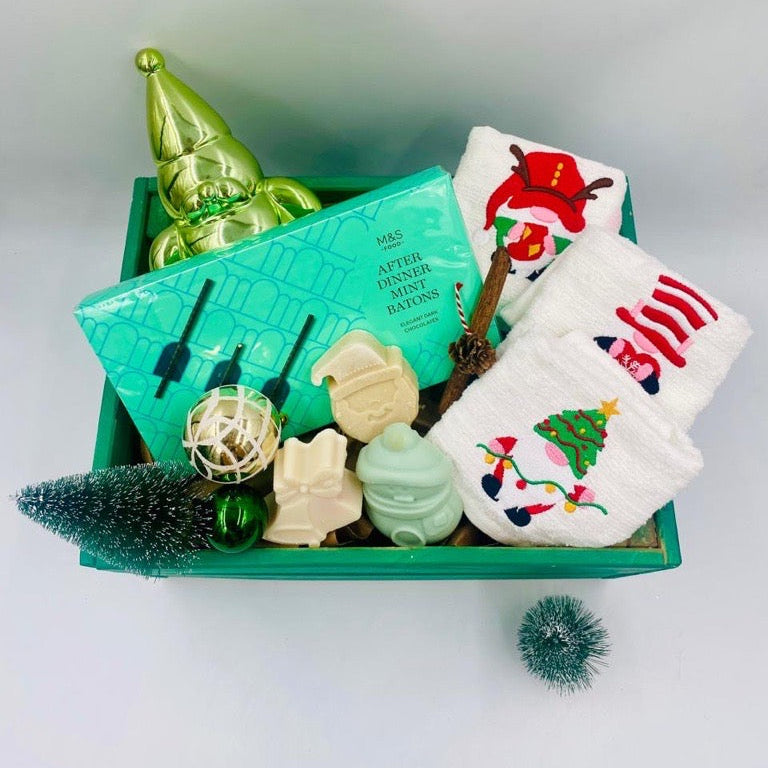 Decorative Christmas items including a green wooden box, small tree, Chocolate Batons box, Christmas towels, natural handmade soaps, and Christmas ornaments 