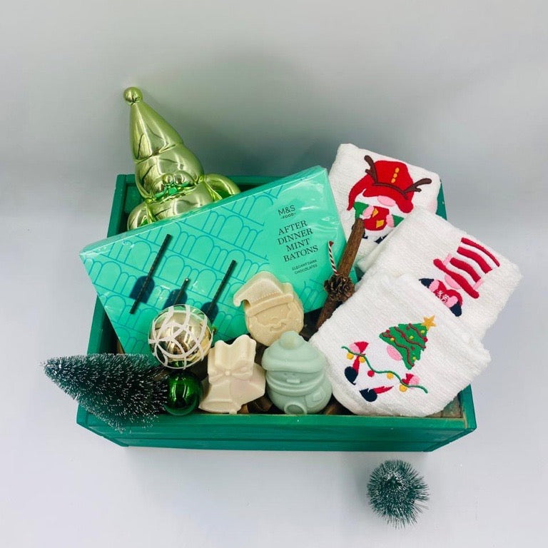 Decorative Christmas items including a green wooden box, small tree, Chocolate Batons box, Christmas towels, natural handmade soaps, and Christmas ornaments 