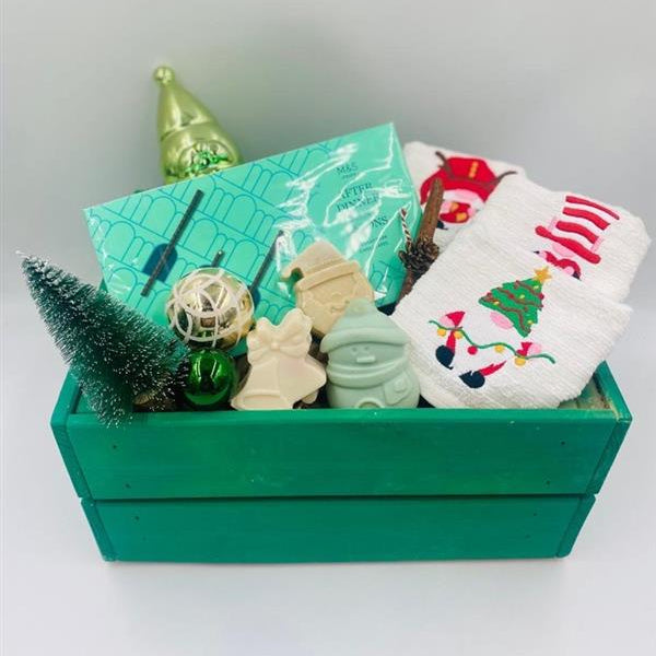 Decorative Christmas items including a green wooden box, small tree, Chocolate Batons box, Christmas towels, natural handmade soaps, and Christmas ornaments 