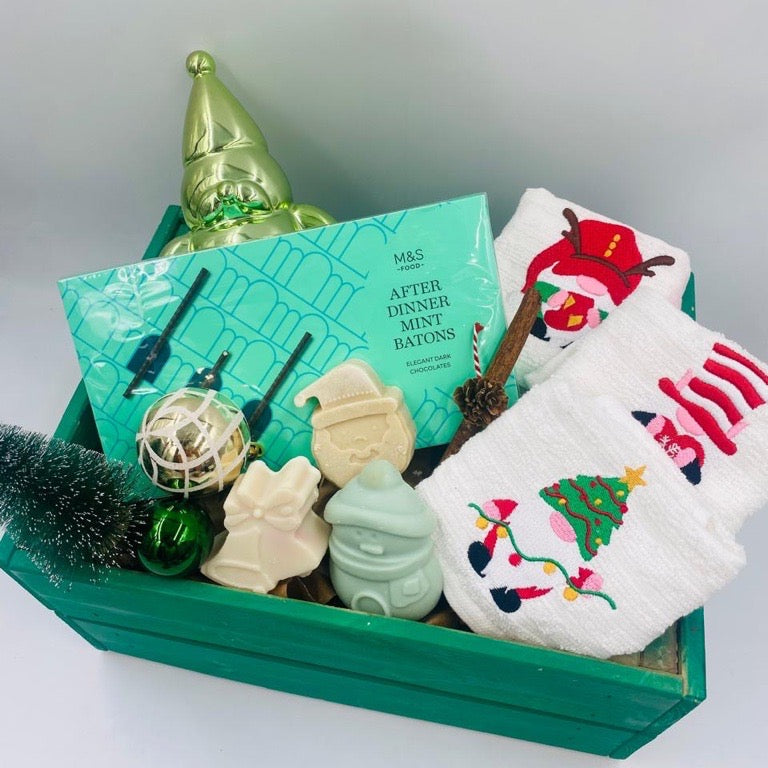 Decorative Christmas items including a green wooden box, small tree, Chocolate Batons box, Christmas towels, natural handmade soaps, and Christmas ornaments 